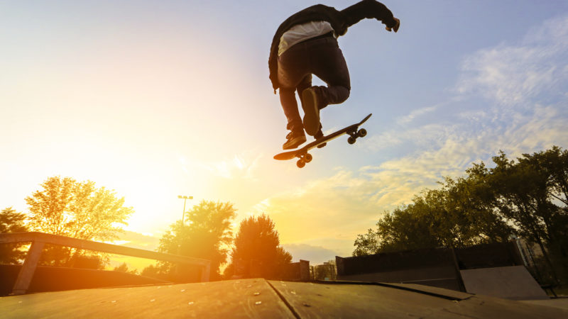 Skateboarding jumping over sunset